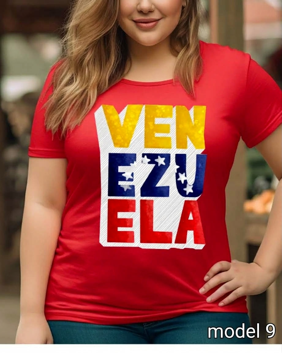 A woman wearing a red short-sleeve t-shirt with a large graphic print reading 'VEN EZU ELA' in yellow, blue, and red with white stars, set against a blurred outdoor background.